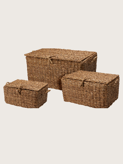 Three woven storage baskets with lids on a beige background