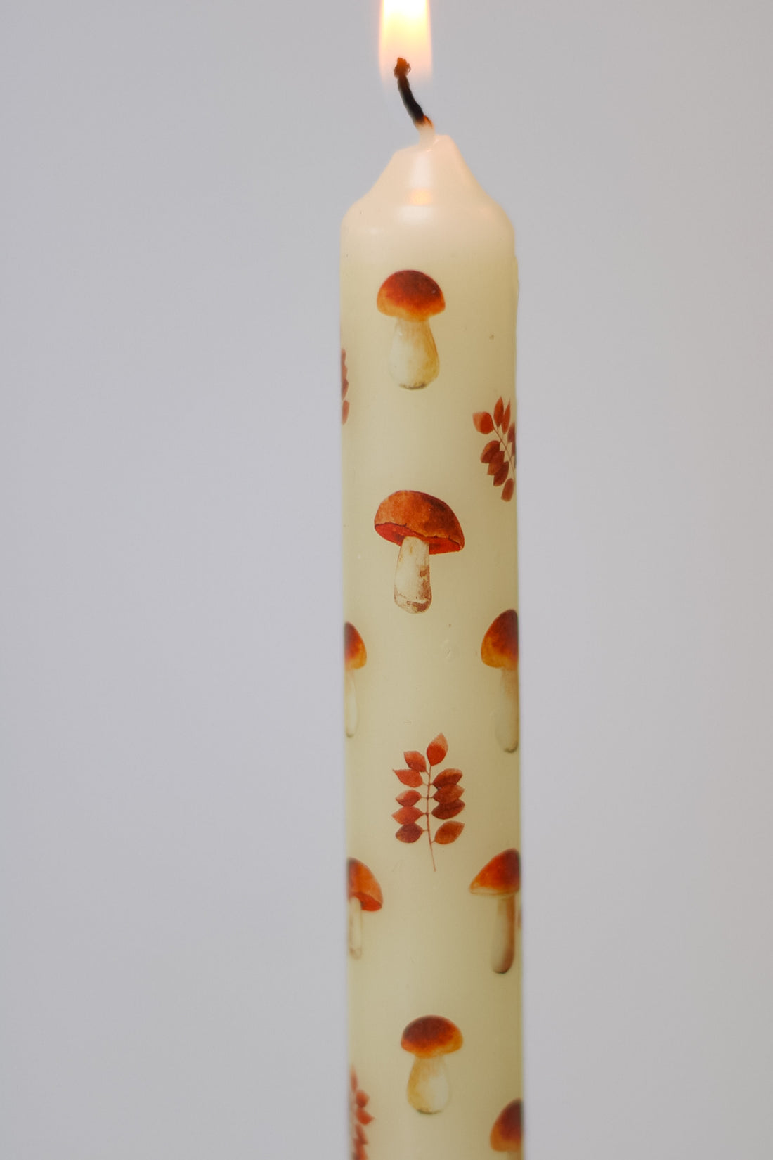 Candle with autumn-themed design on a grey background