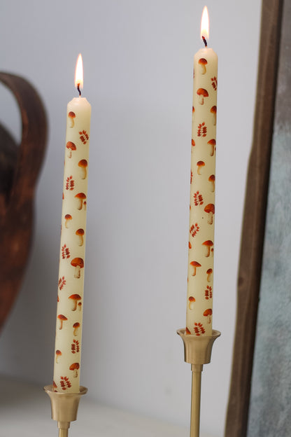 Two candles with mushroom pattern on a plain background
