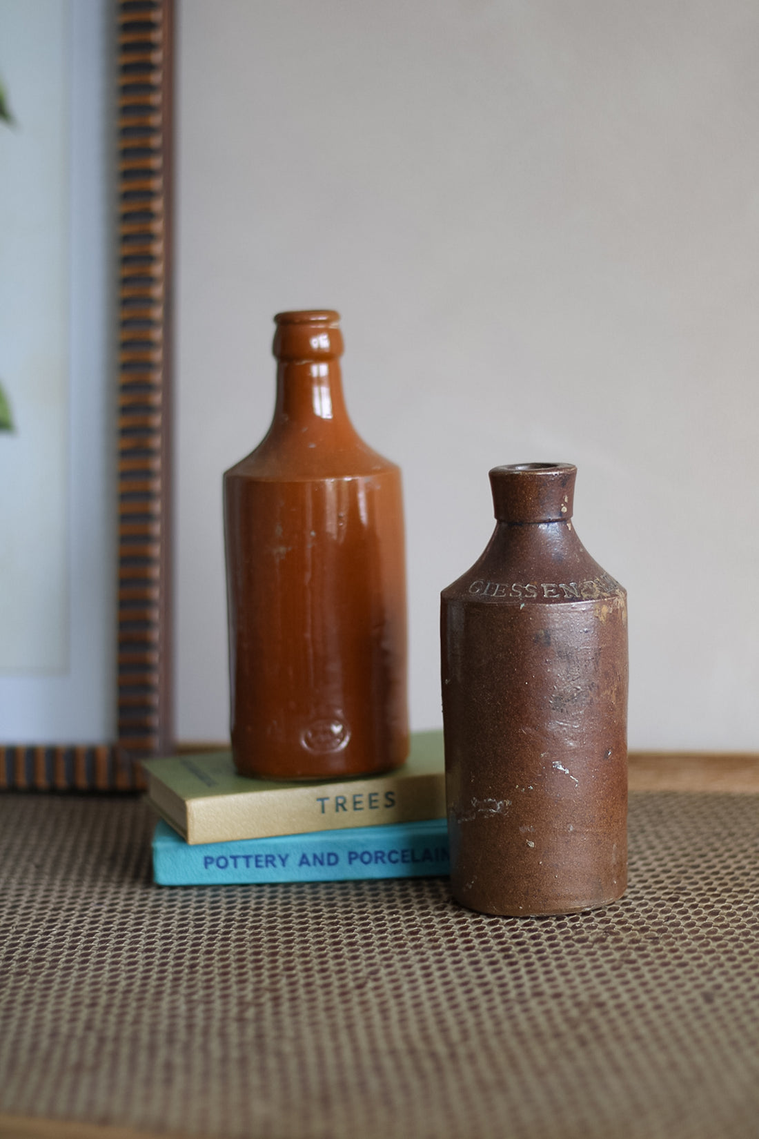 Two brown ceramic bottles on a textured surface with a book in the background.