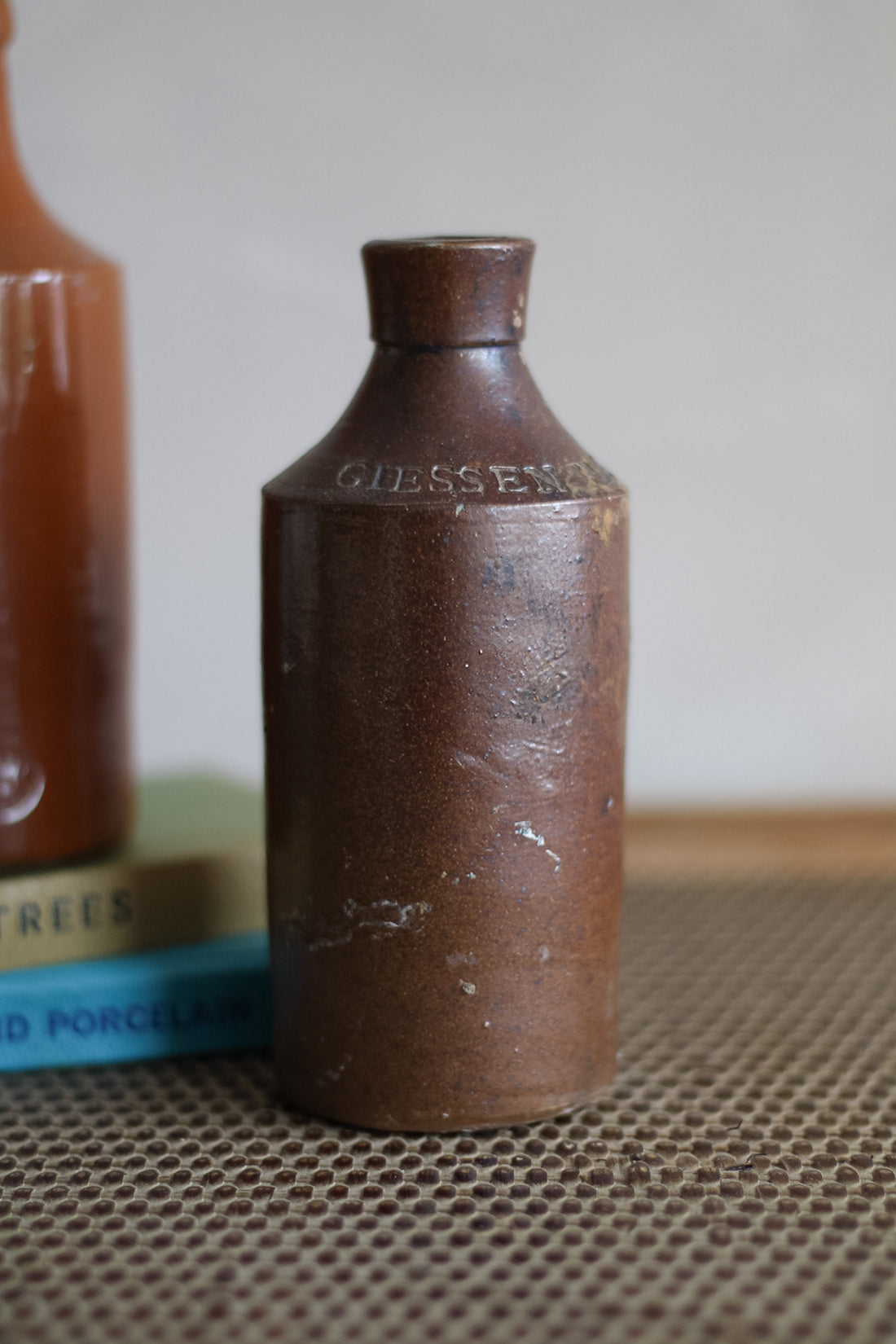 Brown ceramic bottle branding on a textured surface.