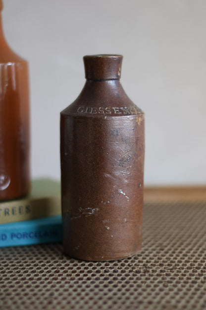 Brown ceramic bottle branding on a textured surface.