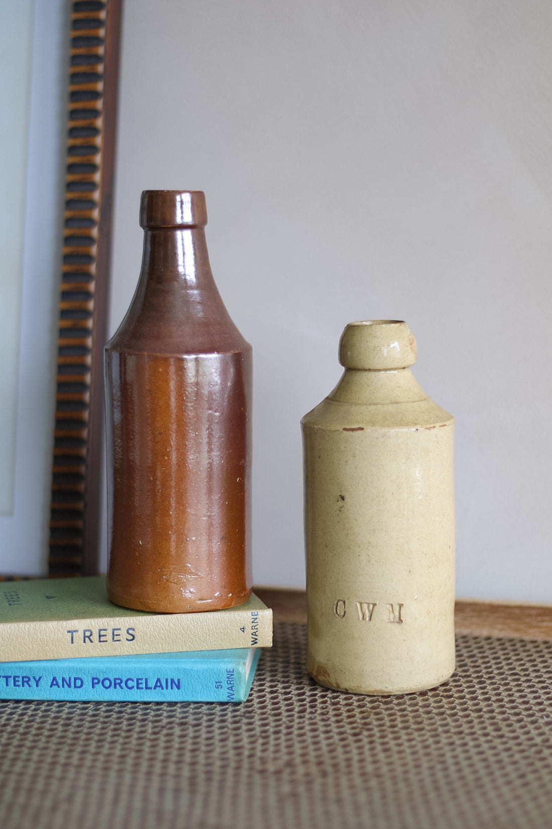 Two vintage stoneware bottles on a textured surface with a neutral background