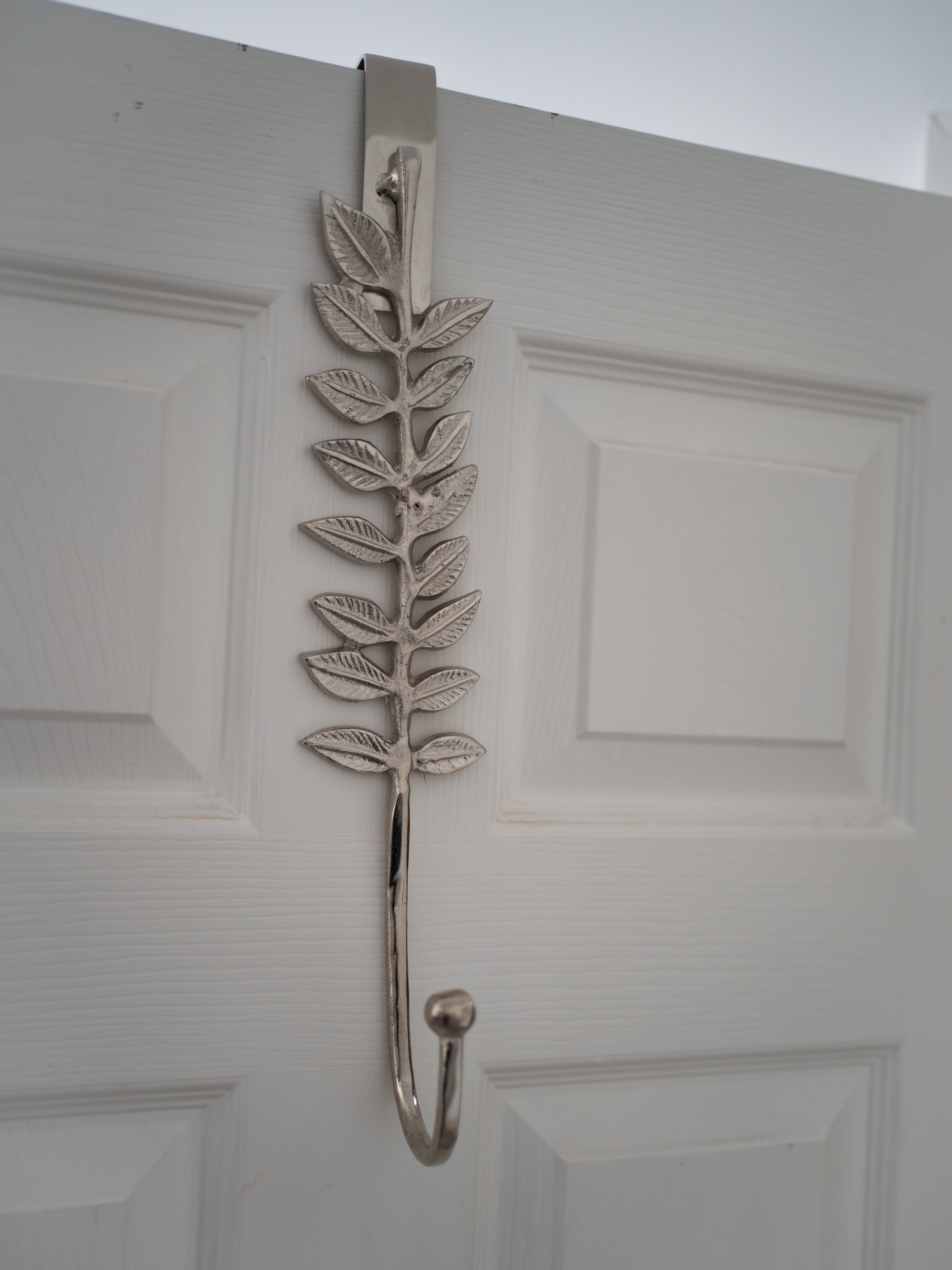 Decorative leaf-shaped wreath hanger on a white door