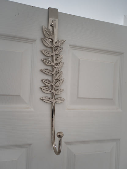 Decorative leaf-shaped wreath hanger on a white door