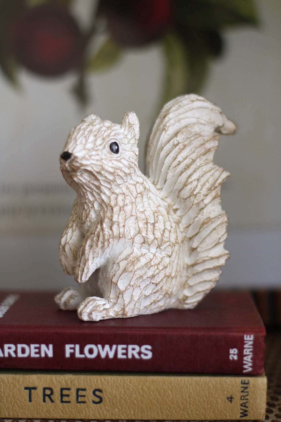 Decorative squirrel figurine on top of books with a blurred background