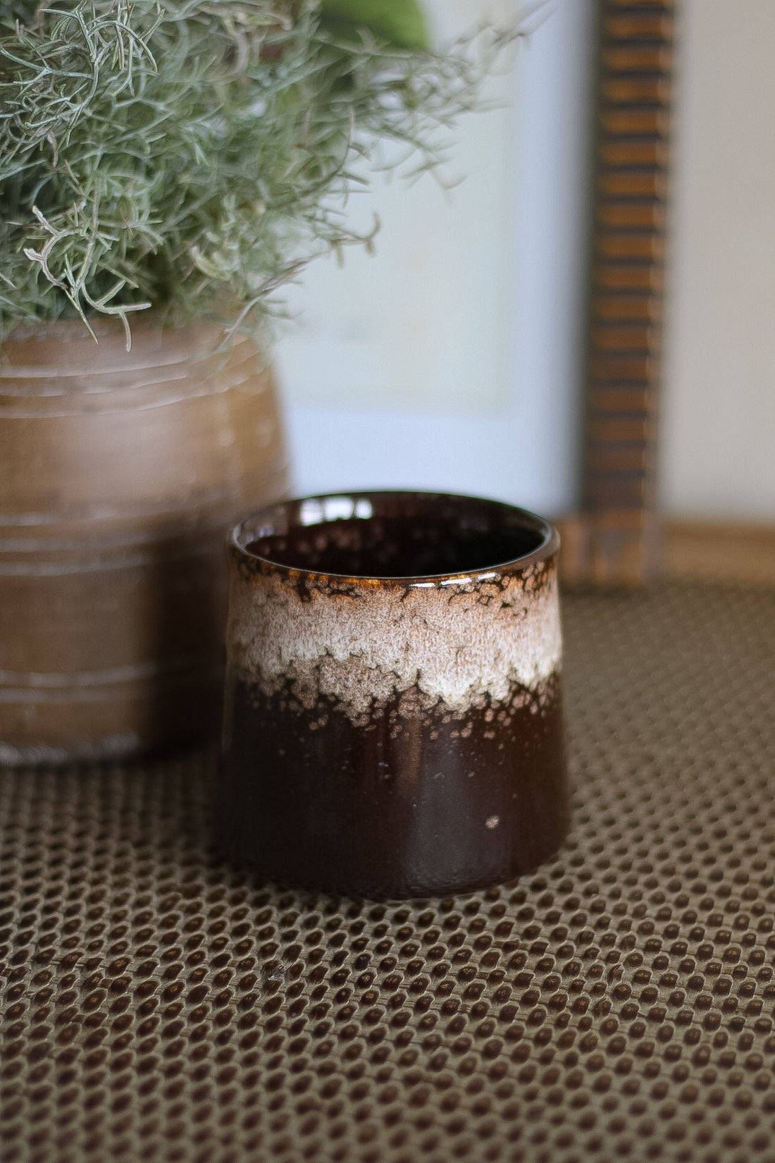 Brown ceramic pot with a textured surface on a patterned surface