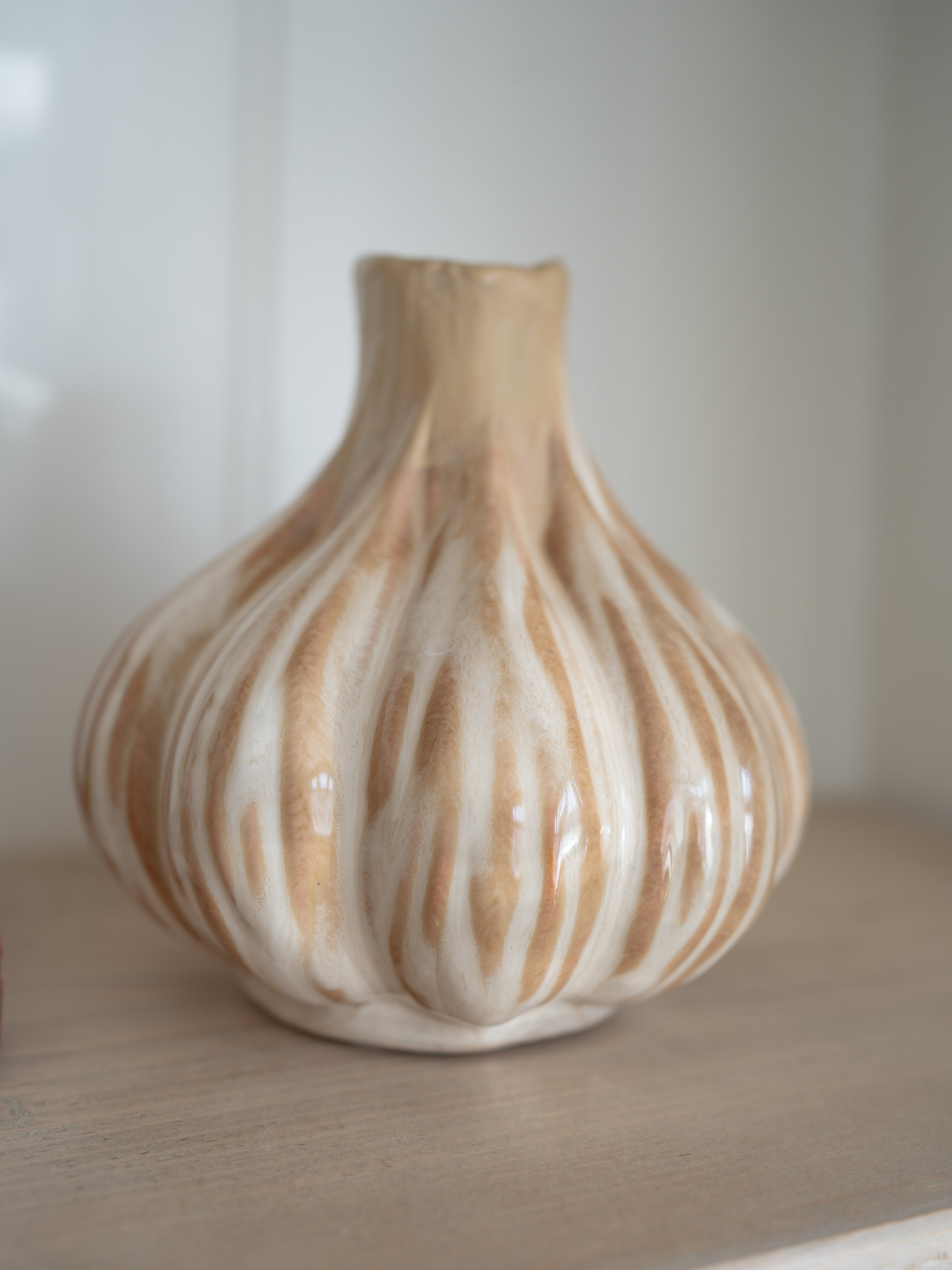 Decorative ceramic beige onion vase with ribbed texture on a neutral background