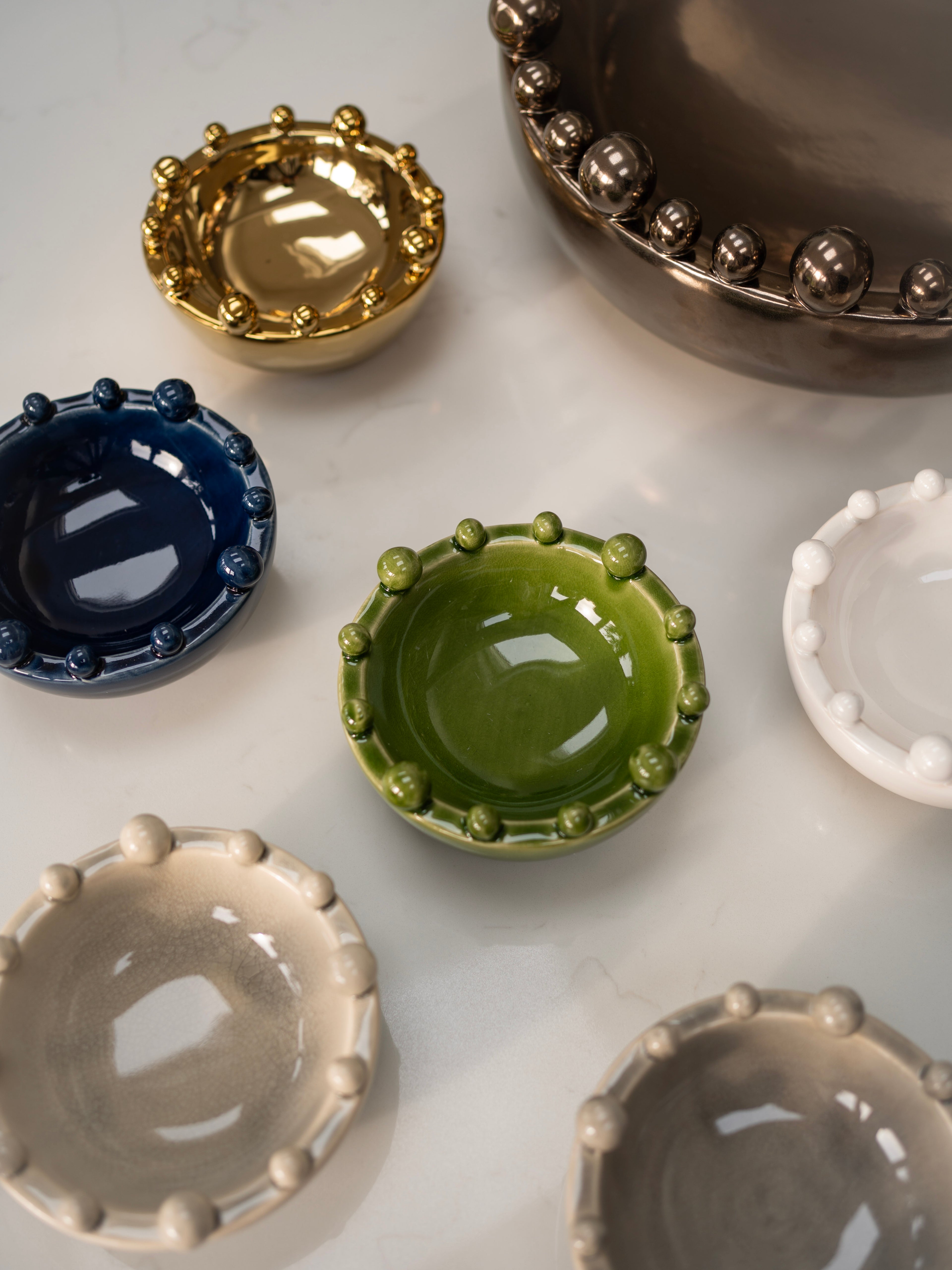 Collection of small ceramic bobble bowls in various colors on a light surface