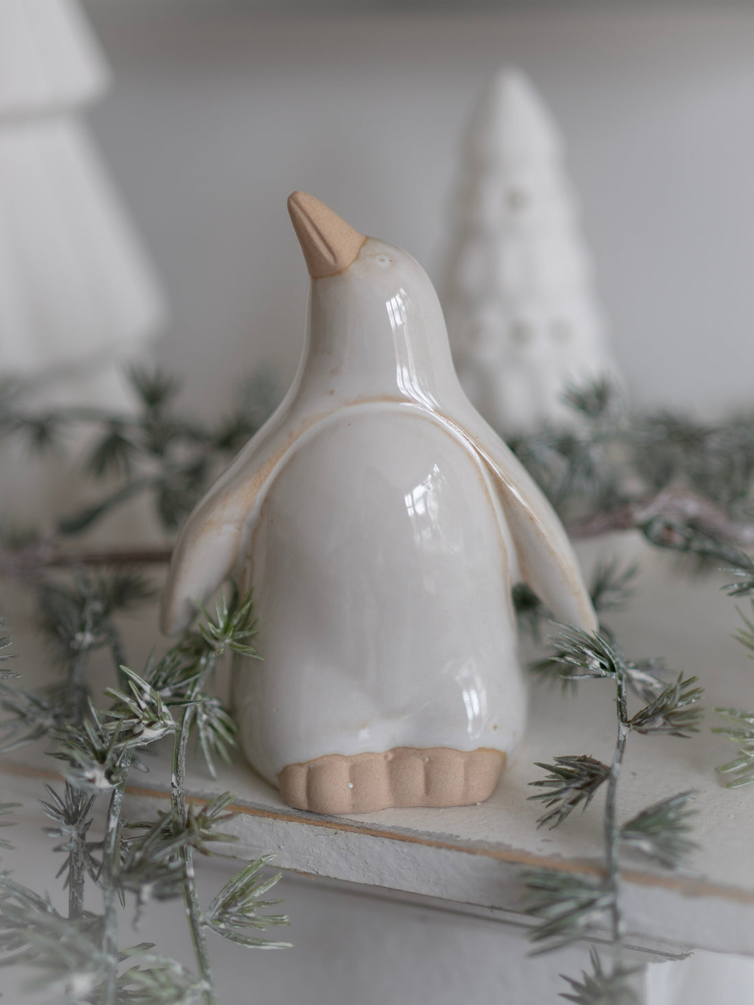 White ceramic penguin figurine on a decorative surface with greenery
