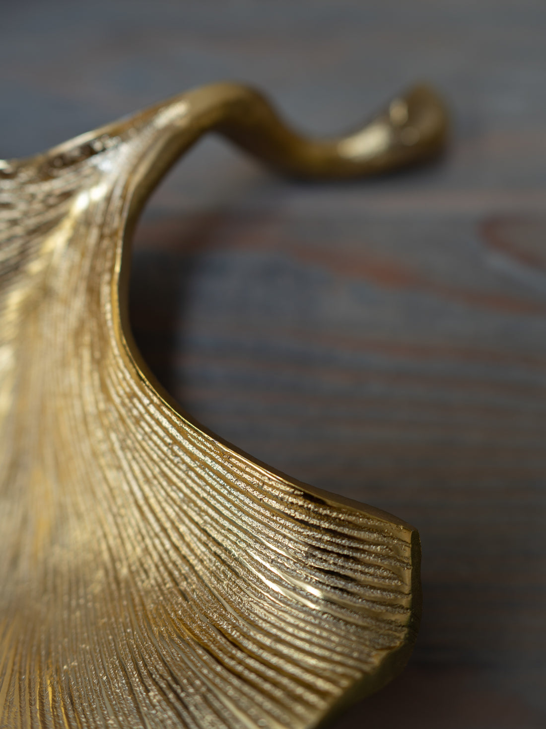Close-up of a gold leaf-shaped trinket dish on a textured surface