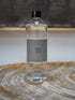 A clear plastic bottle of Scented Senses Smoke fragrance oil with a black cap and a gray label, sitting on a rustic wood slice coaster.