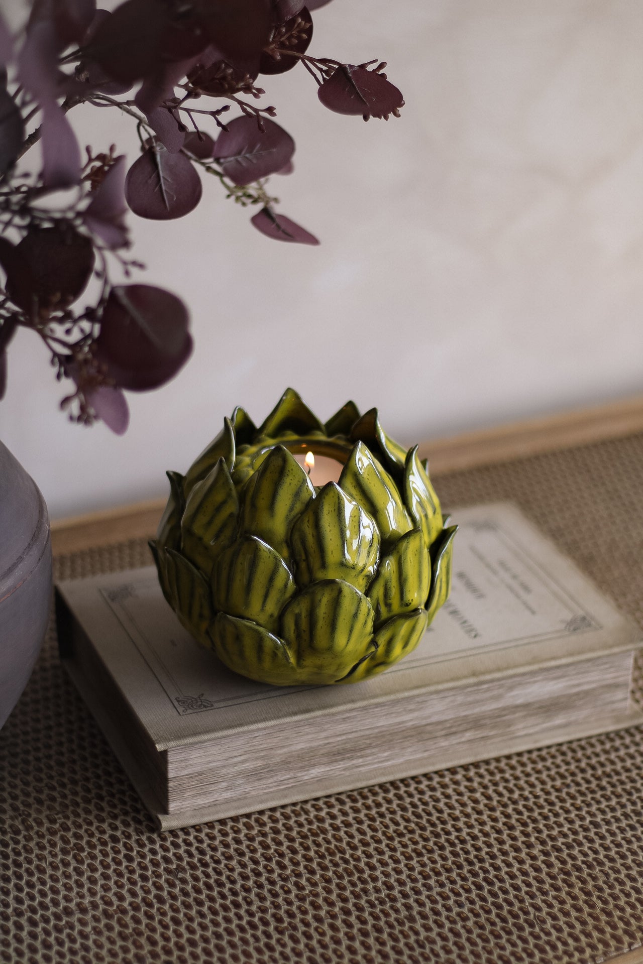 Artichoke-shaped candle holder on a wooden surface with a blurred background