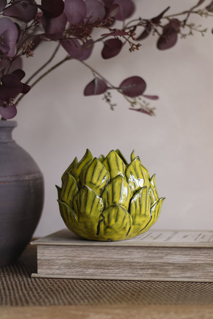 Decorative ceramic artichoke on a book with a blurred background