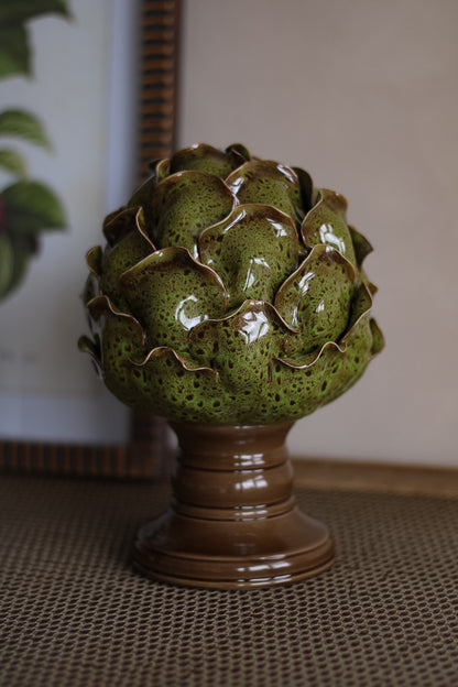 Decorative ceramic artichoke on a pedestal with a neutral background
