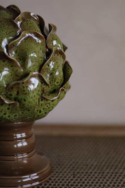 Ceramic artichoke sculpture on a pedestal with a neutral background