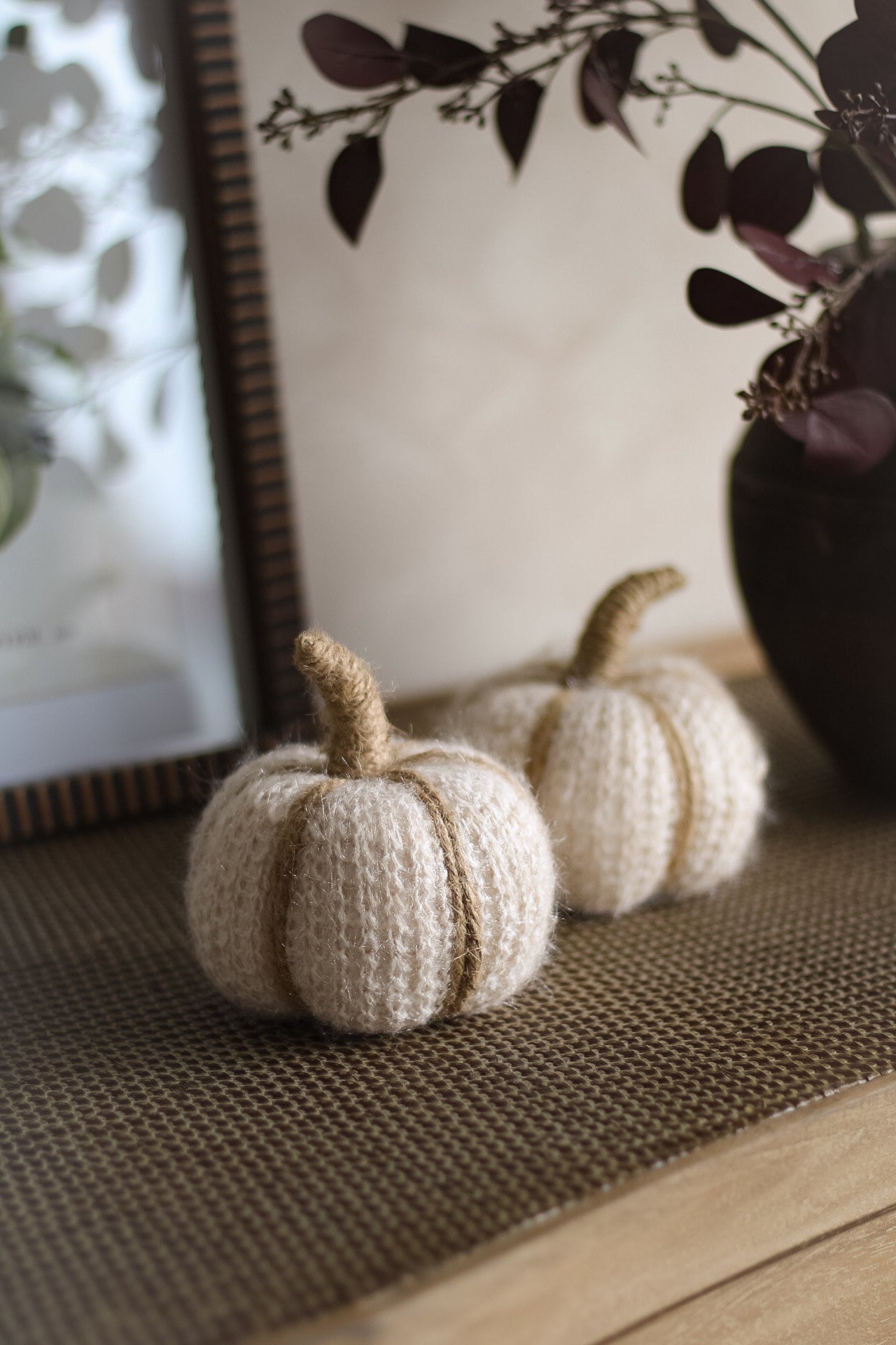 Knitted pumpkins on a textured surface with a blurred background