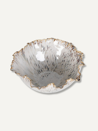 A handcrafted ceramic bowl with a flared, organic rim, featuring a textured speckled glaze in white, gray, and black with a metallic gold edge.