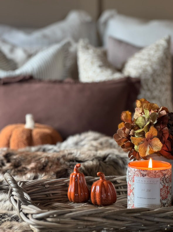 Decorative setting with pumpkins and a candle on a textured surface, likely in a home interior.
