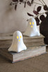 Two ghost-shaped LED decorations with glowing yellow eyes on top of books.