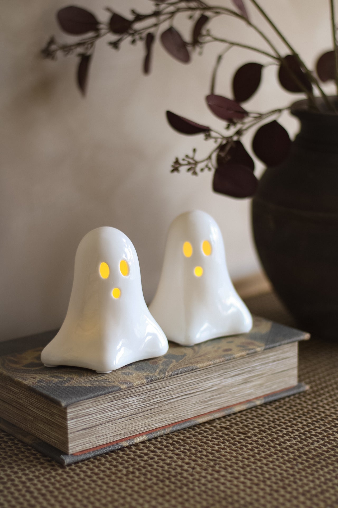 Two ghost-shaped LED decorations on a book with a blurred background