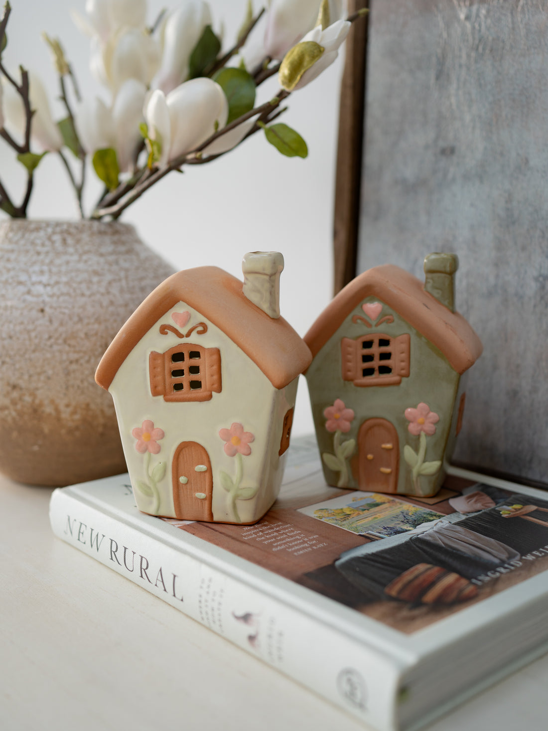 Two small ceramic houses on a book with a decorative background