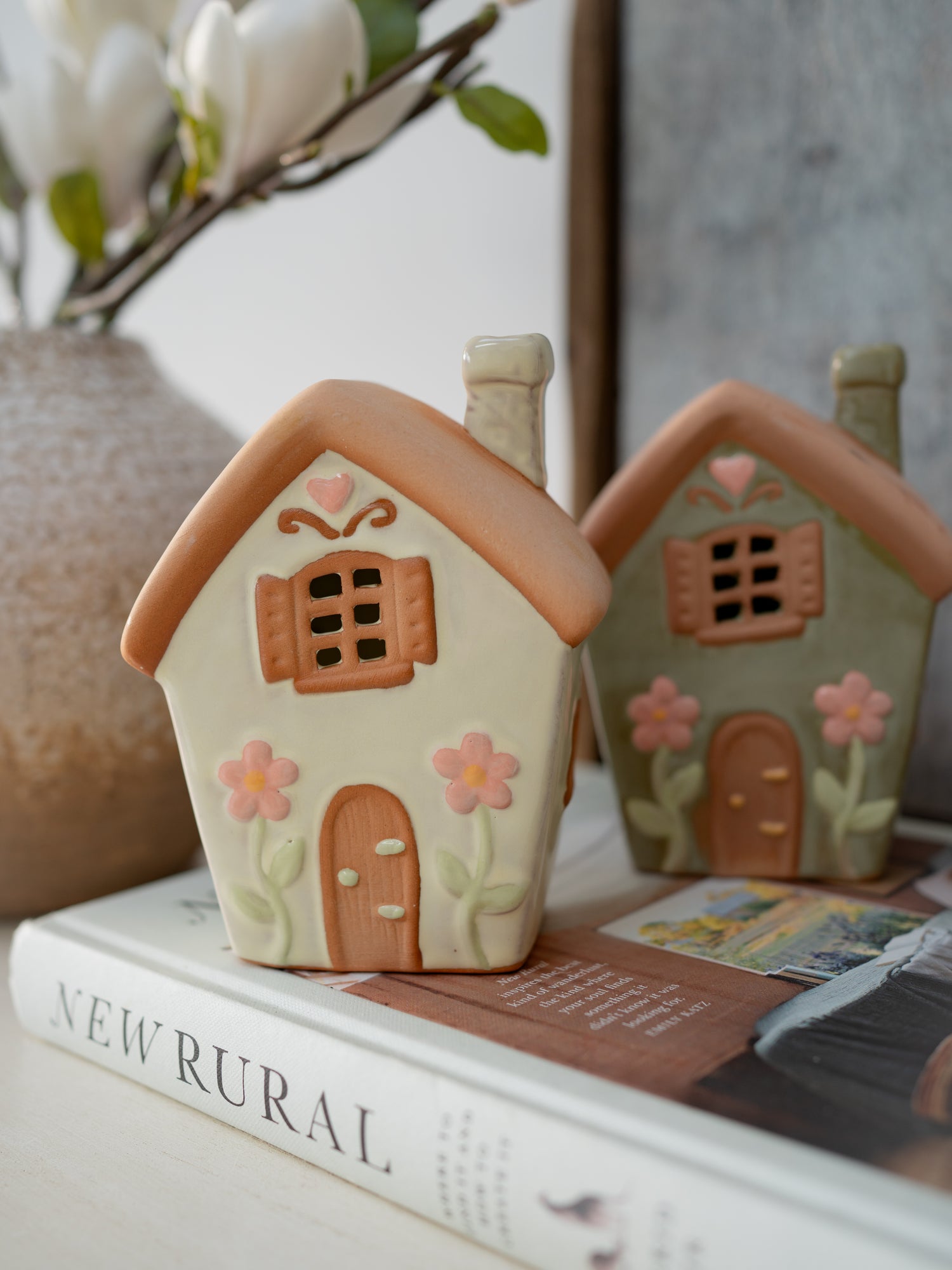 Two small ceramic houses with floral designs on a book