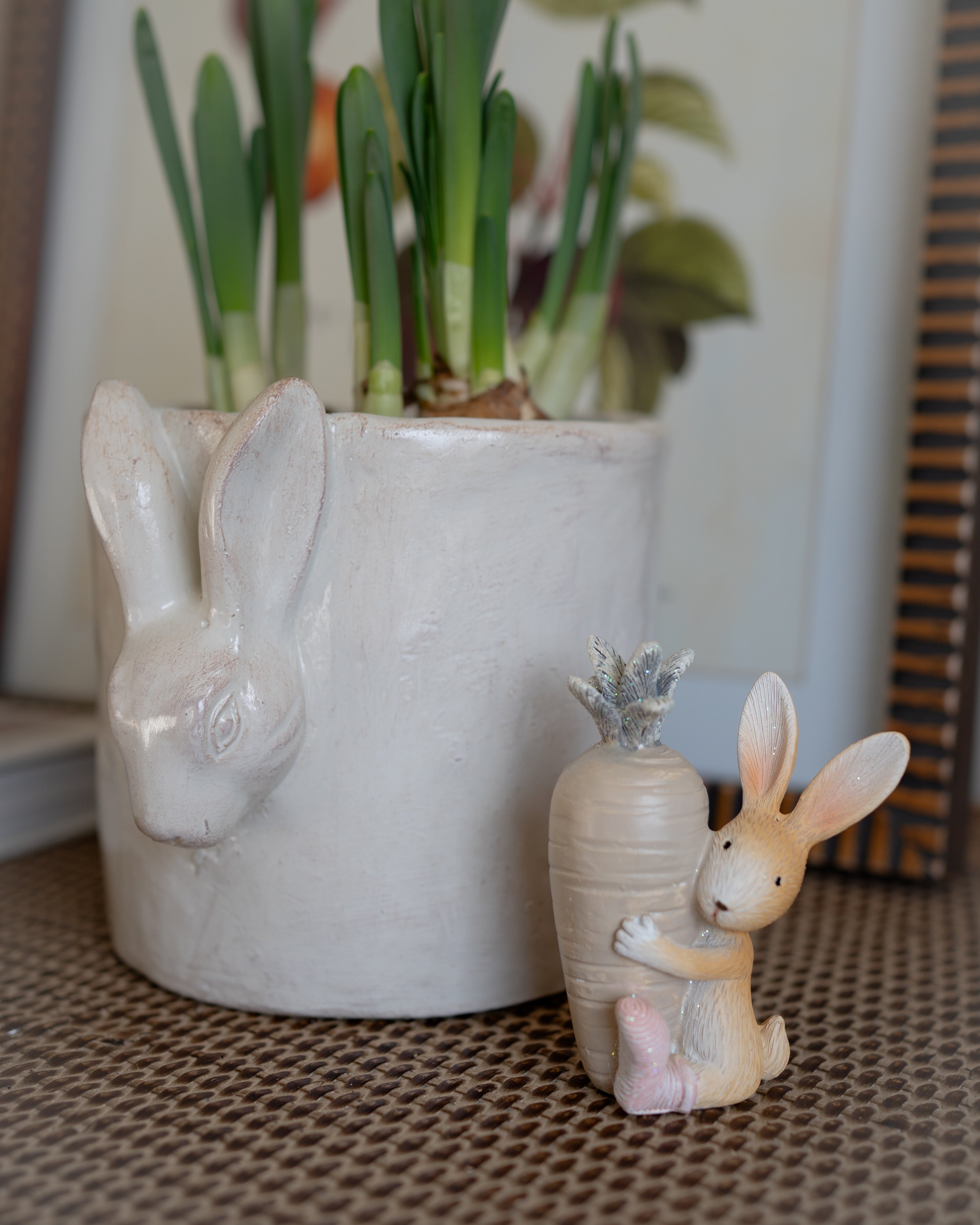 Ceramic rabbit planter with a small rabbit figurine and a succulent on a textured surface.
