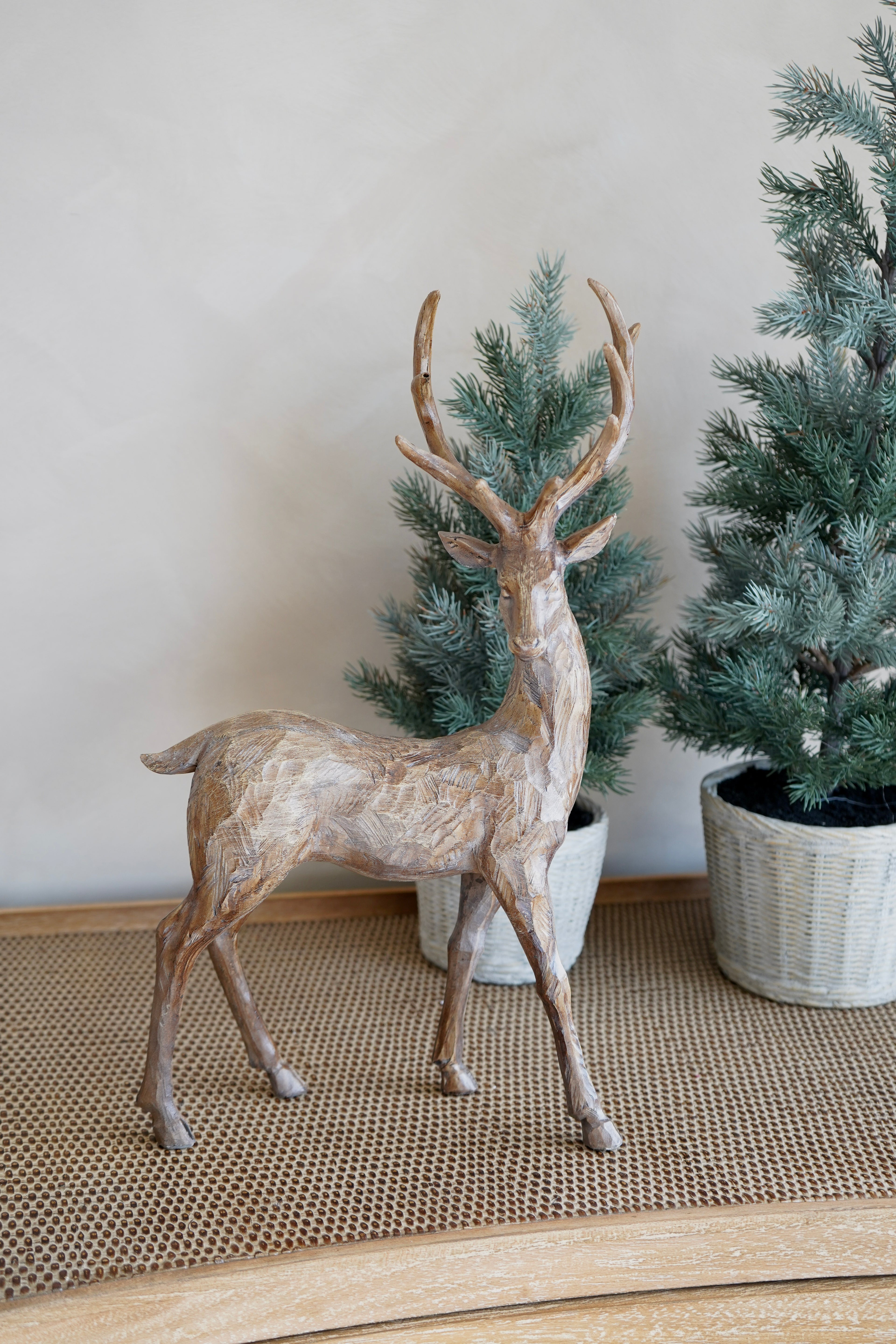 Decorative deer figure with two small potted trees on a neutral background