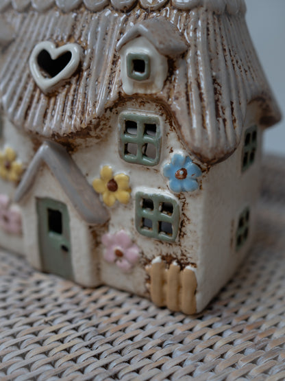 Ceramic house ornament with floral decorations on a textured surface