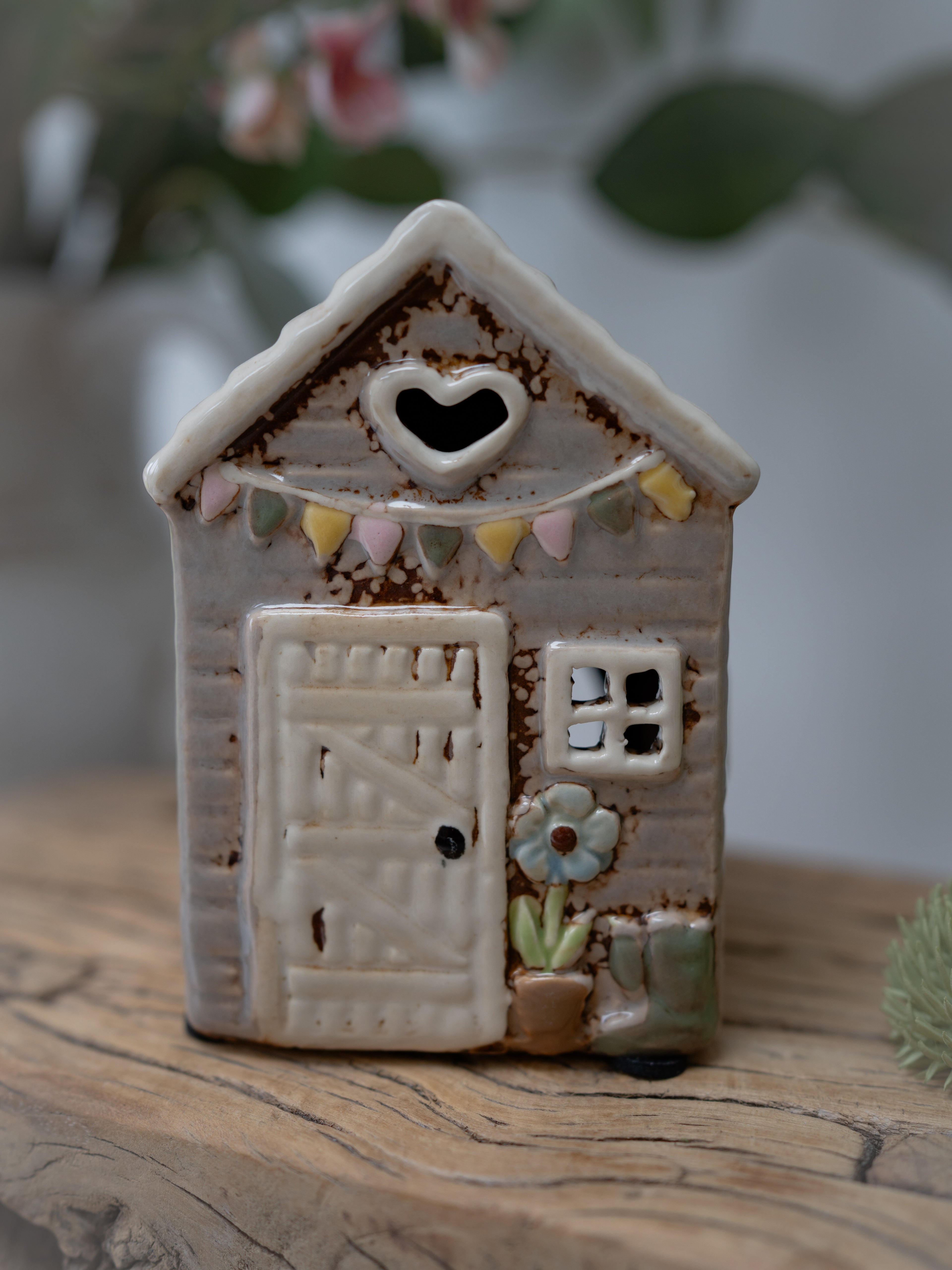 Small ceramic house with decorative elements on a wooden surface