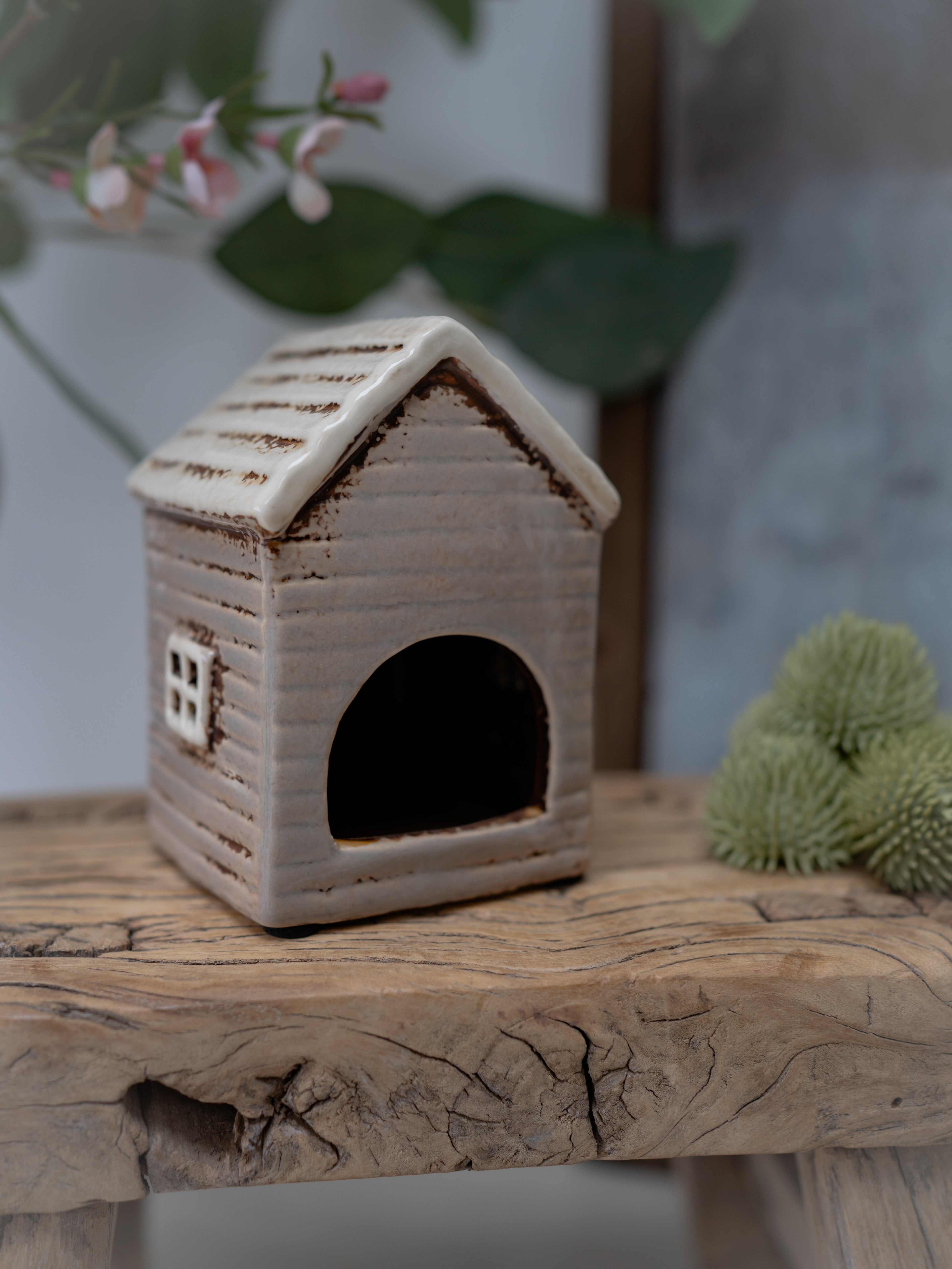 Small ceramic house on a wooden surface with a blurred natural background