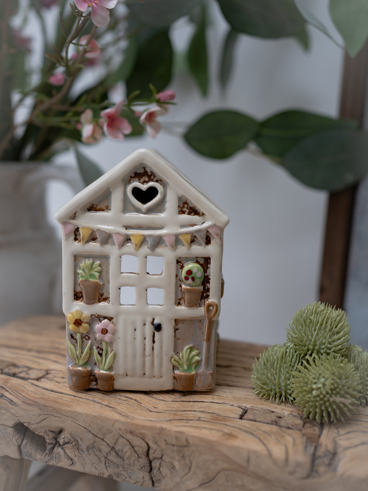 Decorative ceramic house with plants on a wooden surface