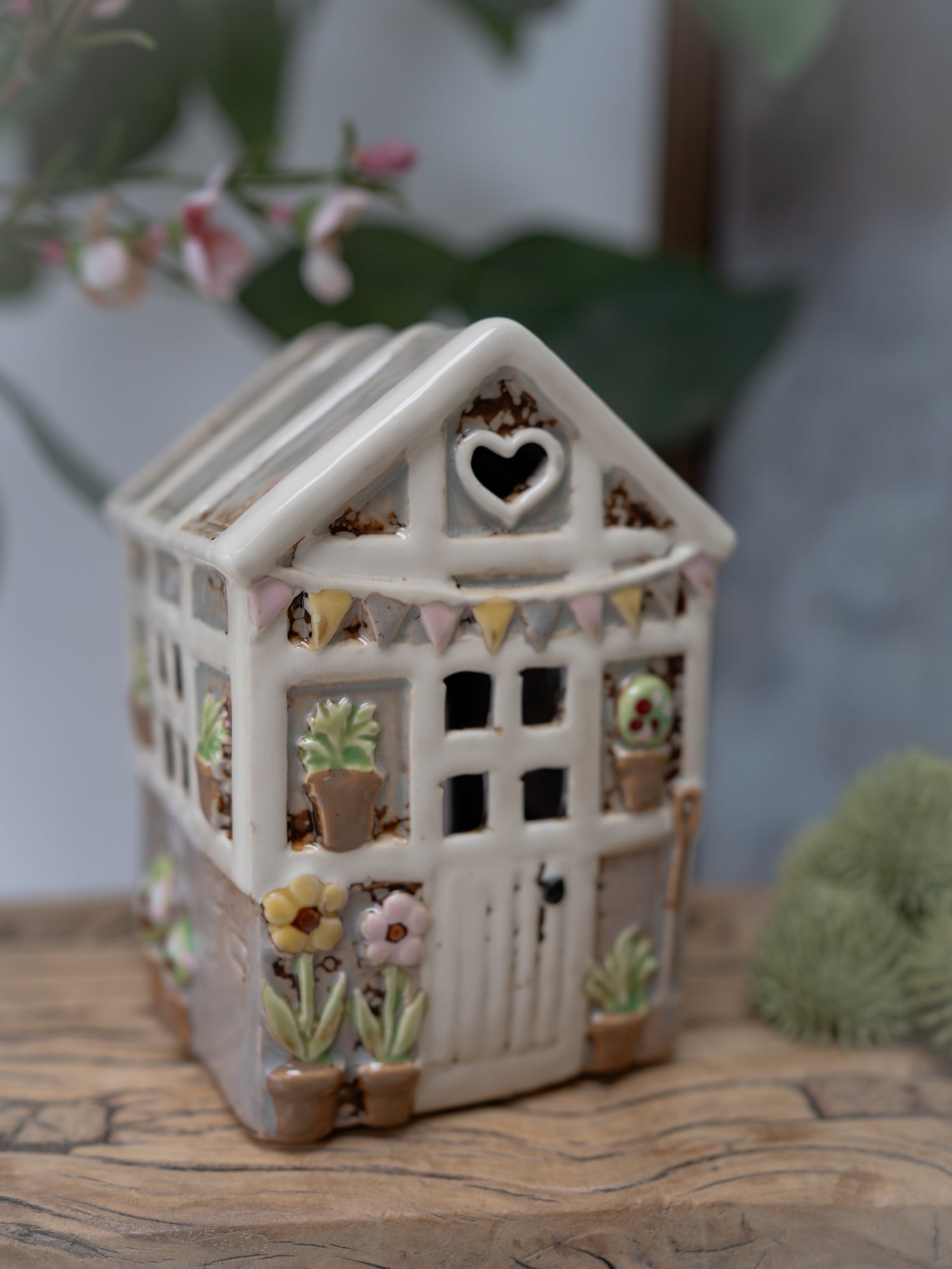 Decorative ceramic house with heart window on a wooden surface