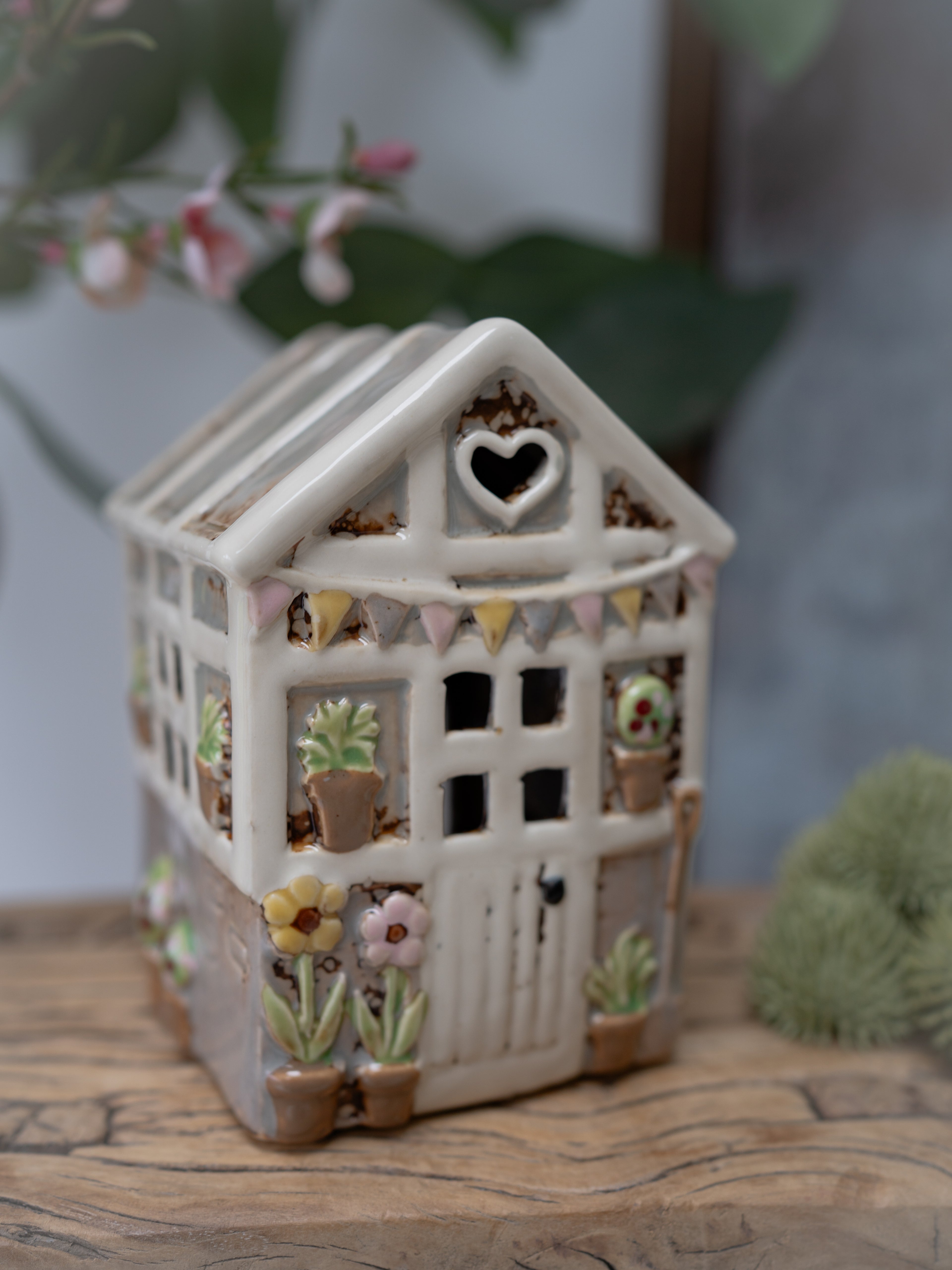 Decorative ceramic house with heart window on a wooden surface