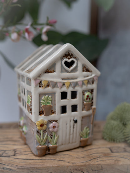 Decorative ceramic house with heart window on a wooden surface