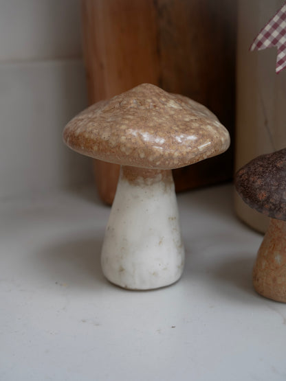 Small ceramic mushroom on a white surface with a blurred background