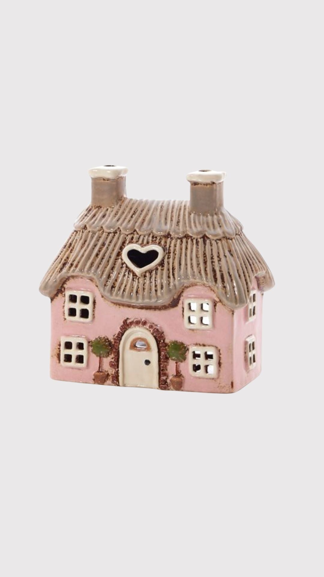 Small pink cottage tea light holder with a thatched roof on a white background