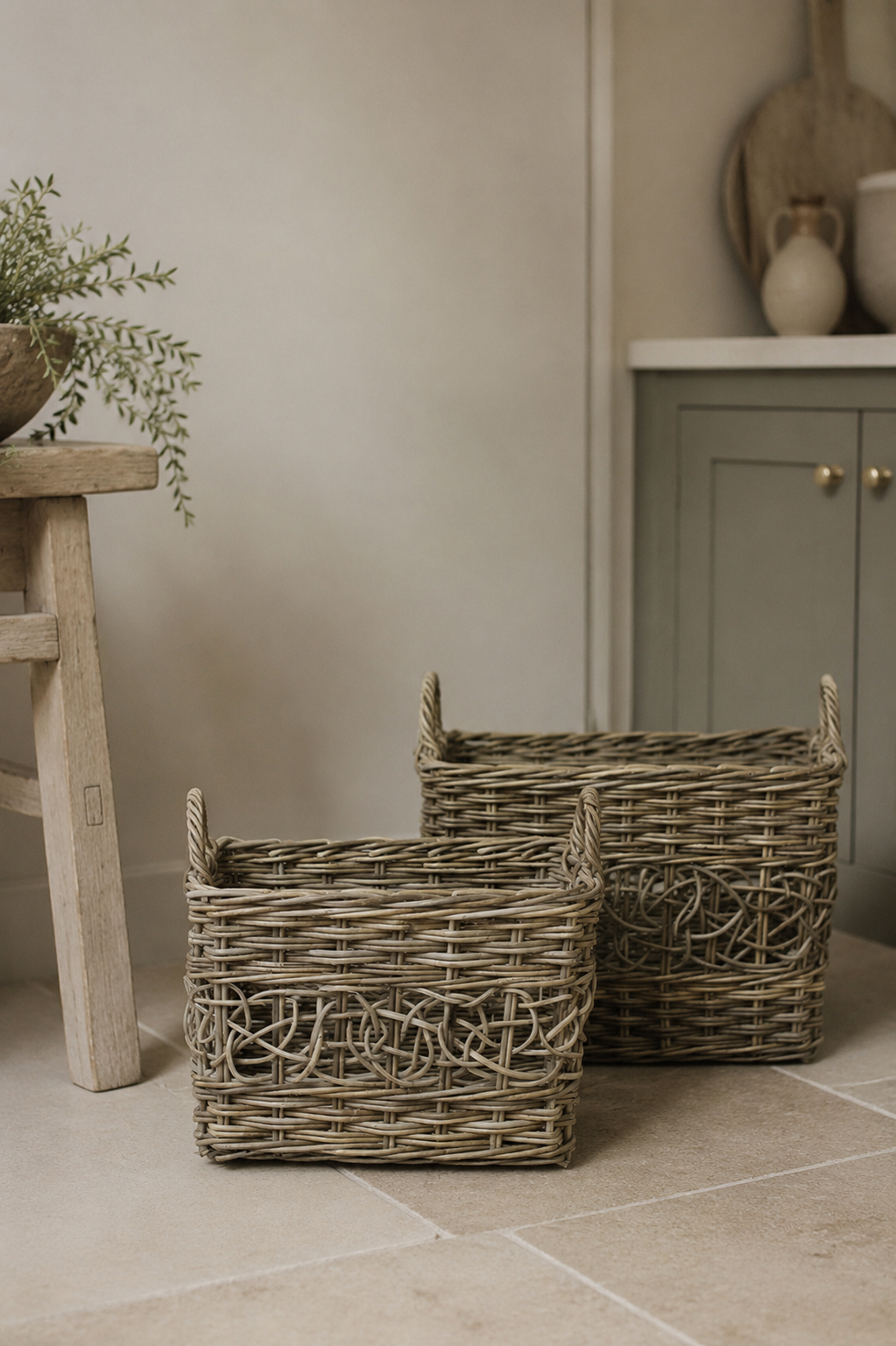 Three woven rustic rattan wicker baskets on a tiled floor with a neutral background