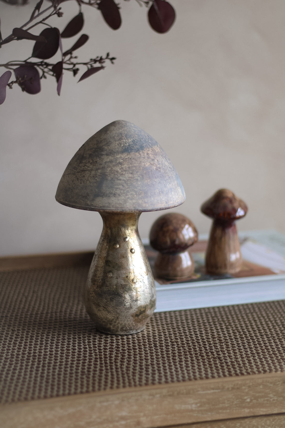 Decorative copper mushrooms on a textured surface with a neutral background