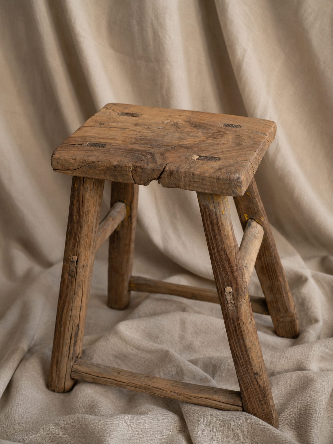 Vintage wooden stool on a beige fabric background