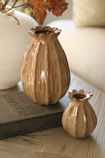 Two ceramic poppy head vases with brown stripes on a wooden surface.