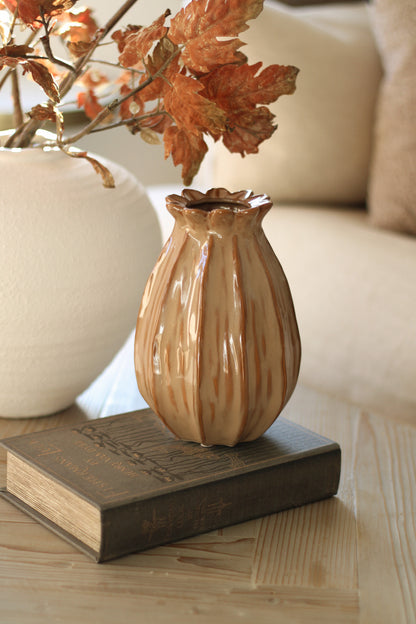 Decorative poppy head vase on a book with autumn leaves in the background
