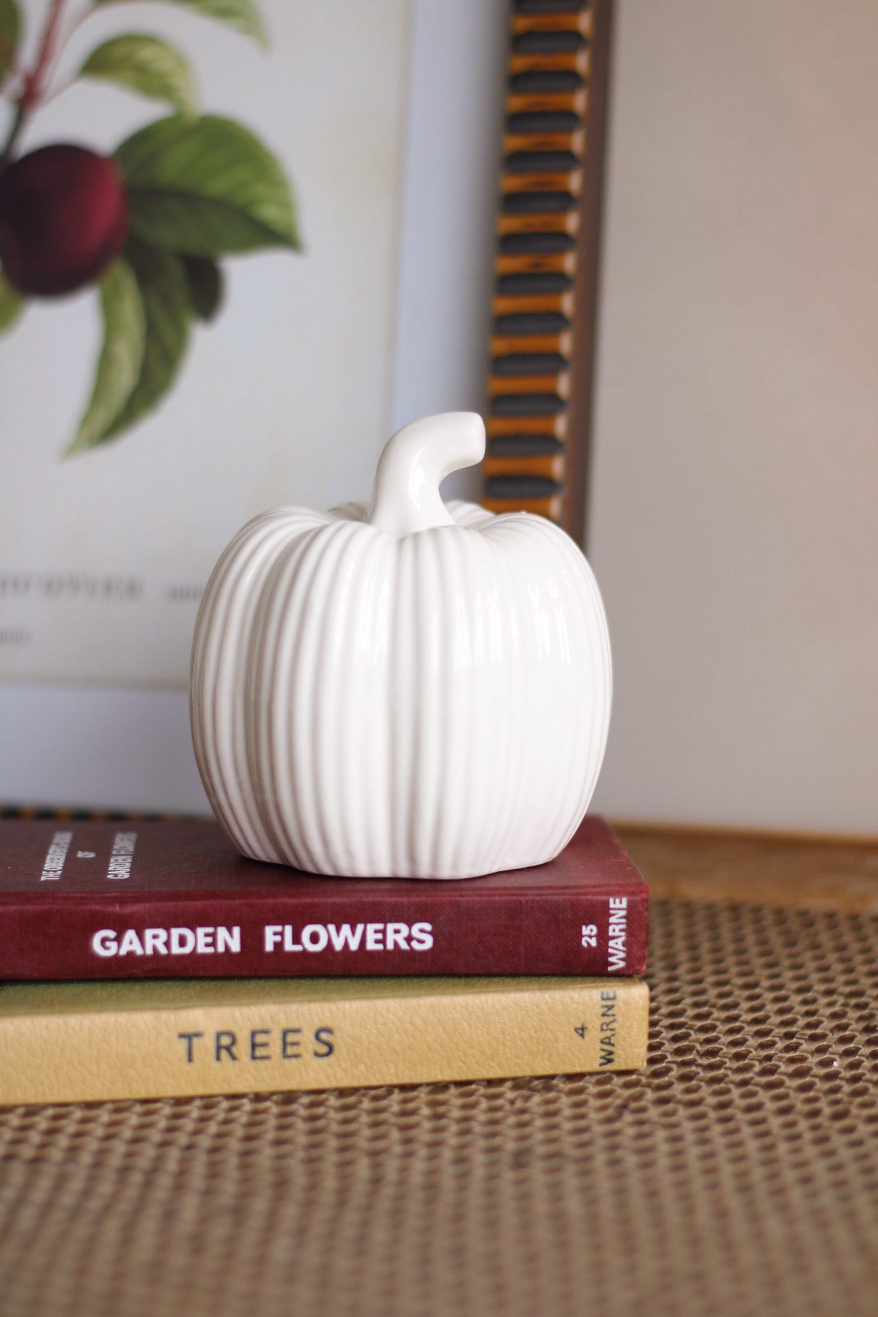 White ceramic pumpkin on top of books with a blurred background