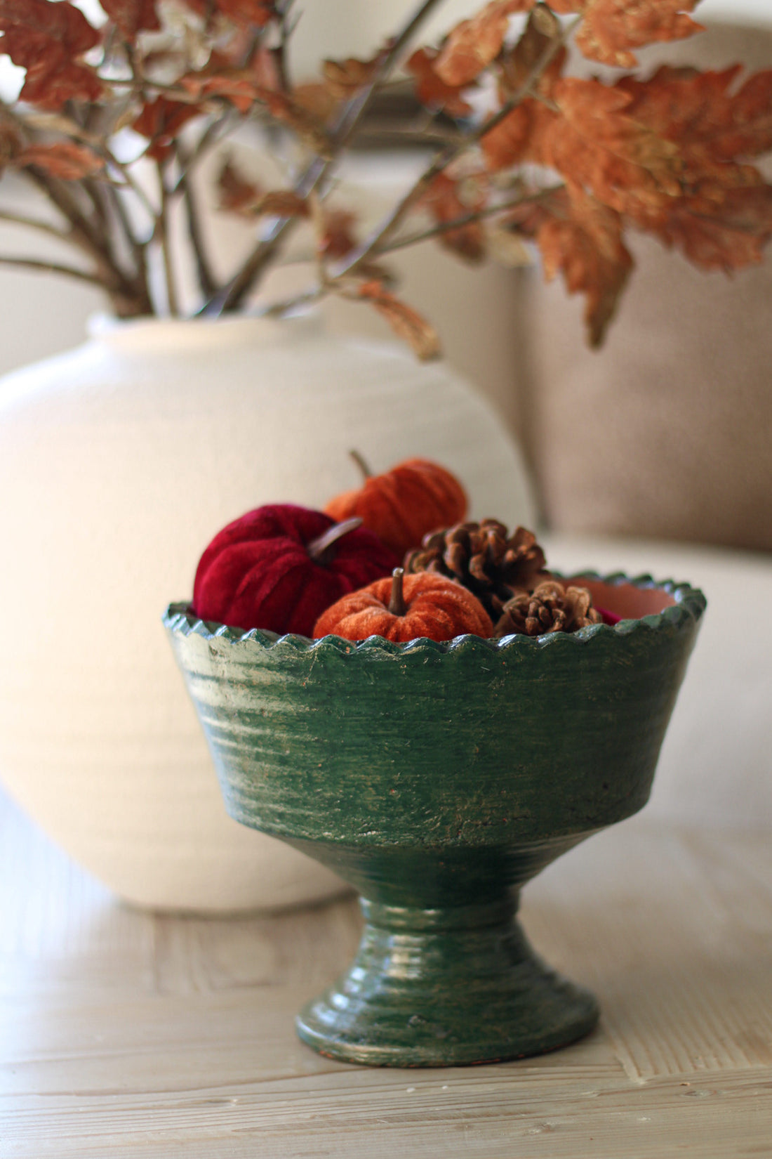 Green terracoota bowl with decorative items on a surface