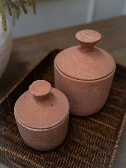 Two terracotta jars with lids on a woven tray