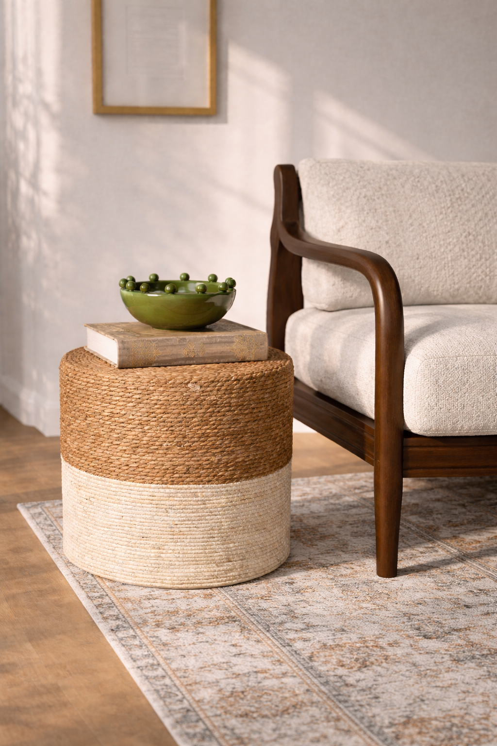 Woven side table with a green bowl and book next to a wooden armchair in a room.