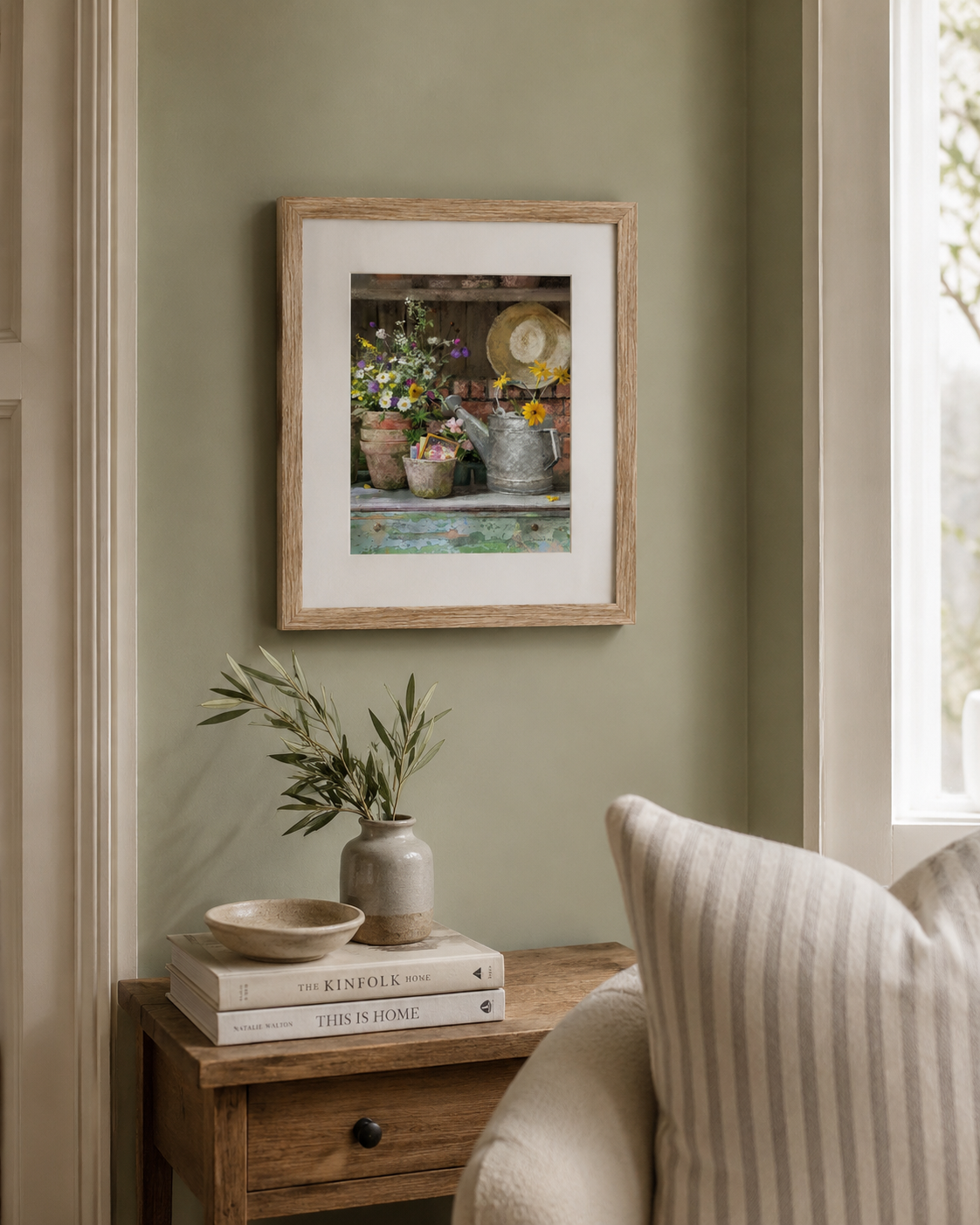 Framed artwork on a wall with a small table and plant in the foreground.