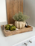 Decorative tray with artichokes and a decorative plant pot with faux spanish moss on a white surface.