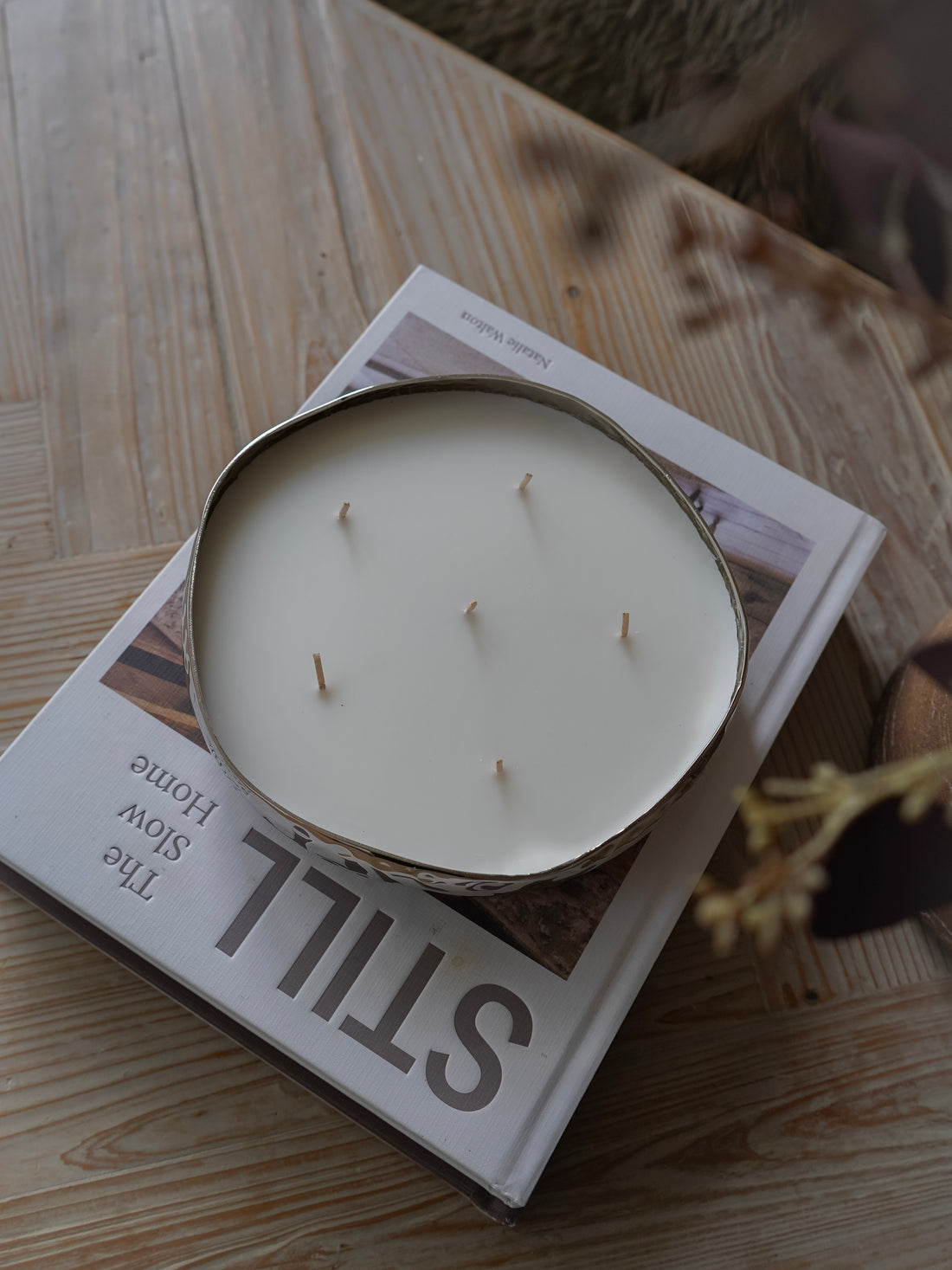Candle in a tin on top of a magazine with  visible